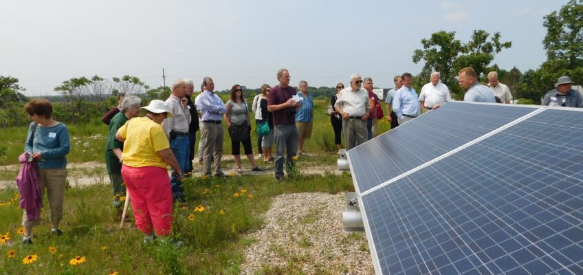 A group of people look at solar panels in a field