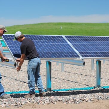 Two men measure and install a solar panel
